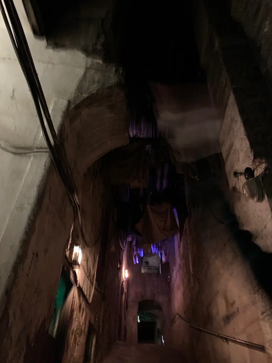 Un callejón subterráneo oscuro y empinado en Mary King's Close, con muros de piedra alzándose a ambos lados y una luz tenue al fondo