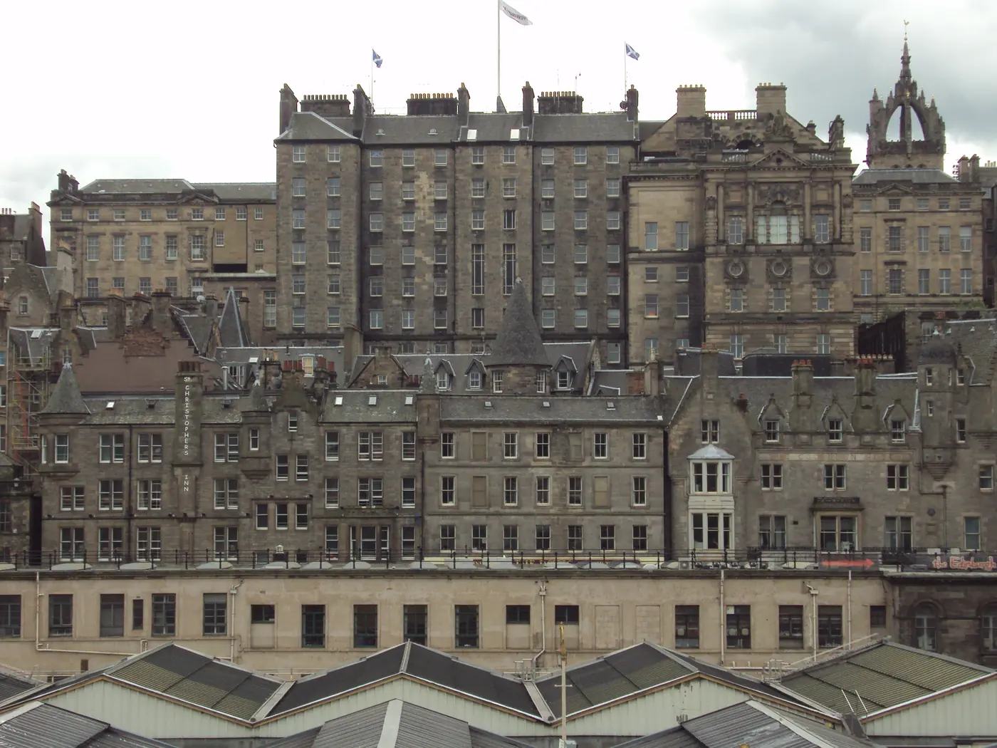 La alta parte trasera del City Chambers de Edimburgo se alza sobre los tejados de la estación de Waverley, con la aguja coronada de St Giles' al fondo