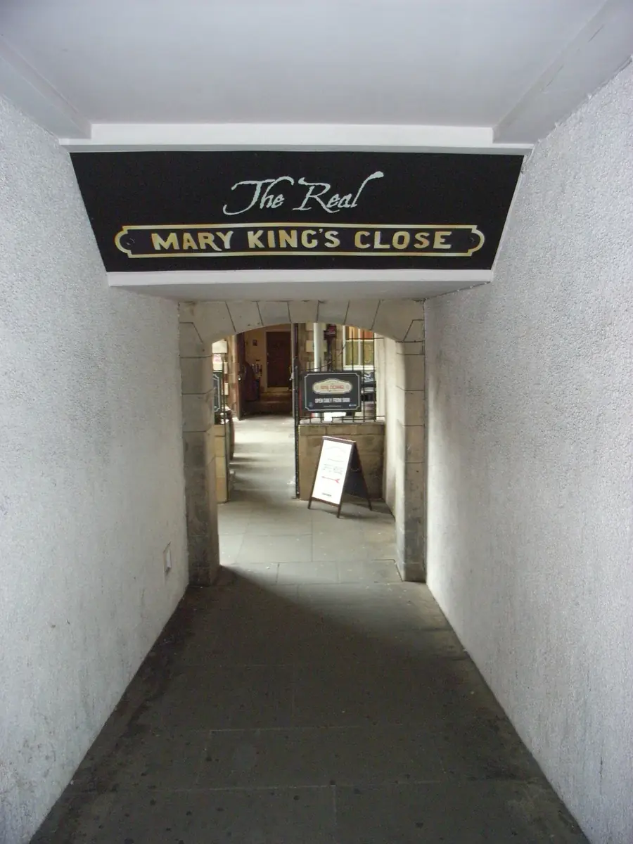 Un pasaje blanco que conduce al tour de Mary King's Close, con un cartel negro y dorado que dice The Real Mary King's Close