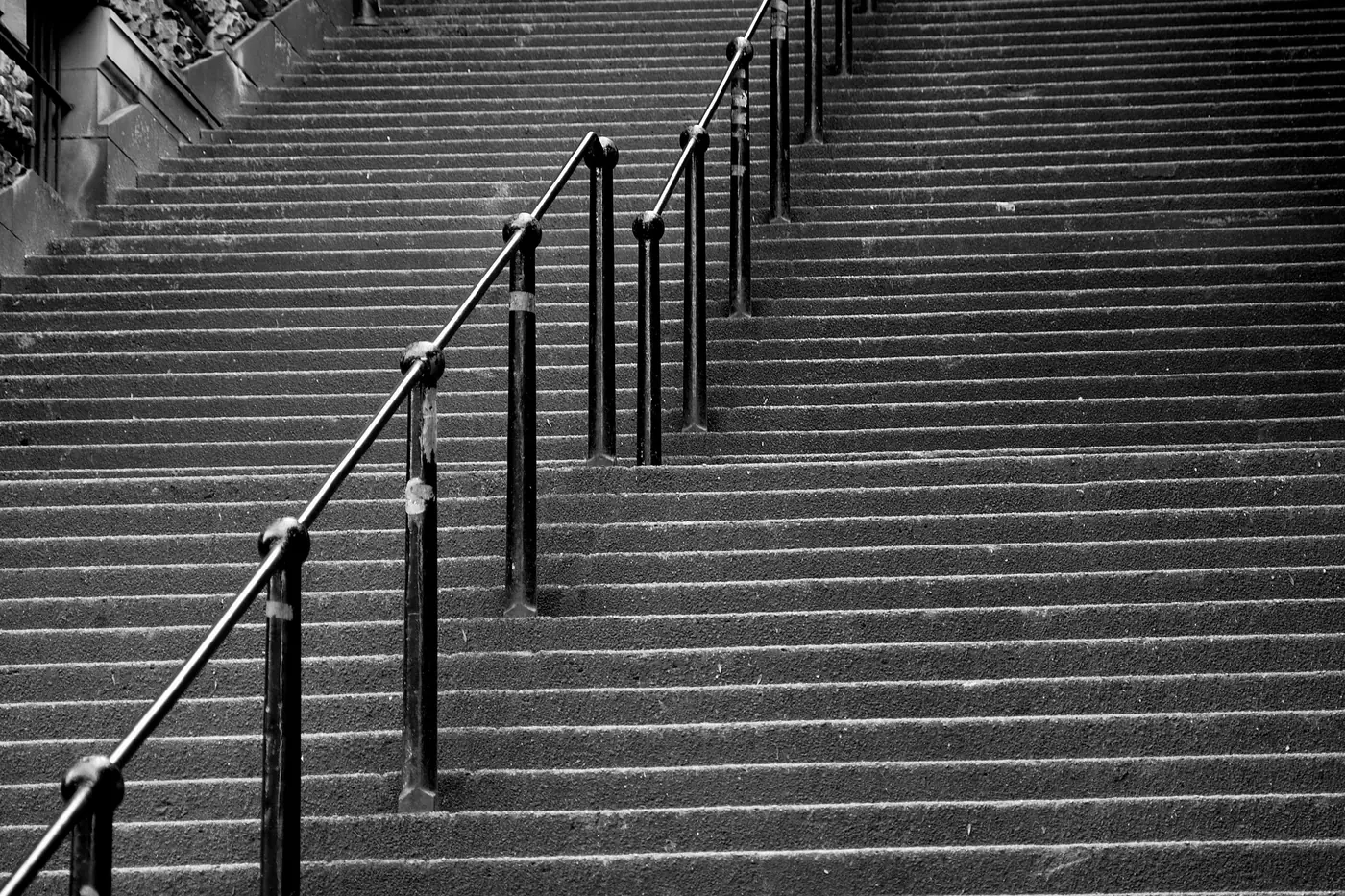 Vista en blanco y negro de la larga escalera de piedra de Warriston's Close, con pasamanos de hierro recorriéndola por el centro